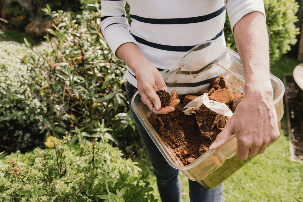 Woman holding coffee grounds in bin