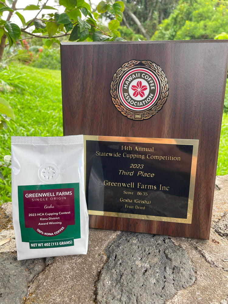 Photo of a bag of Gesha Kona Coffee on a rock wall next to a 3rd place award plaque from the Hawaii Coffee Association