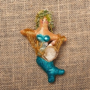 Decorative and sparkling mermaid carrying shells.